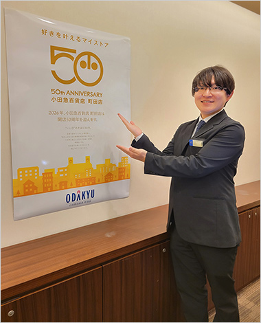 50周年ポスター前の田口さん