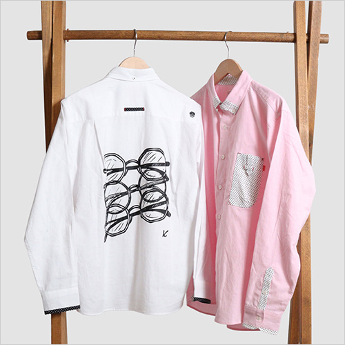 長袖シャツ メガネケース3(Glasses case3) (綿80％・ポリエステル20％／ドット部分：綿100％) 18,700円  ＜河谷シャツ＞の人気シリーズ「メガネケース」から、新しい表情をまとった「メガネケース3」が登場しました。今回は総柄ではなく 無地のオックス生地 を採用。そのシンプルさが背景となり、背面に並ぶ3つのメガネのラバープリントがよりくっきりと際立つデザインに仕上がっています。胸元にはお馴染みの立体メガネケースポケット を配置。ホワイトとピンクの2色展開。無地だからこそ着回しやすく、背面のプリントがコーディネートの主役となる一着です。 ※その他参考品