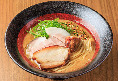 天草大王の濃厚鶏白湯らーめん(1杯) 1,300円  熊本県が誇る日本最大級の地鶏「天草大王」の旨みを凝縮した濃厚鶏白湯スープ。麺には国産小麦「春よ恋」を主軸に、「焔神」と全粒粉を配合し、ゆで伸びしにくいしなやかなコシと力強い弾力を実現。小麦本来の豊かな香りが広がる特製麺が、濃厚なスープと絶妙に調和する一杯です。