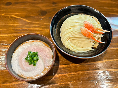 ワタリガニの濃厚つけ麺(1杯) 1,800円  ワタリガニを香味野菜とともにじっくり煮込み、甲羅ごと炊き出すことで生まれる“濃密なカニのコク”と“香りの余韻”が特徴です。 つけダレは一口目からワタリガニ特有の甘みと深い旨みが押し寄せ、後半は芳ばしい甲殻の香りがふわりと広がる重層的な味わい。もちもち太麺とあわせると、カニの旨みが絡み合います。
